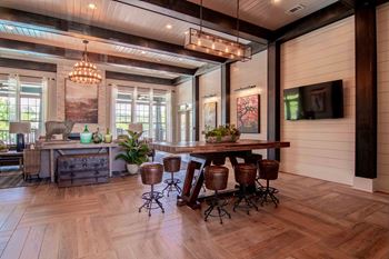 a large living room with a wooden floor and a table with stools  at Century New Holland, Georgia